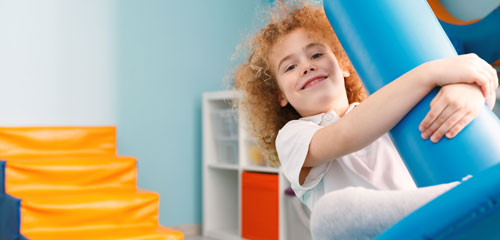 A boy rocks on a piece of equipment in a sensory room