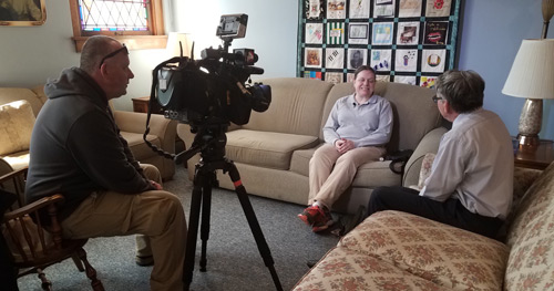 Shelbi Hindel sits on a couch across from NBC4 Columbus Reporter Rick Reitzel as a cameraman films their conversation